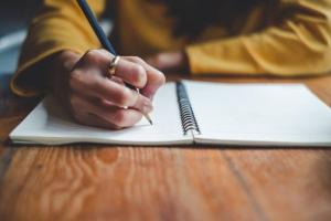 A woman writing in a ledger | CRC NI